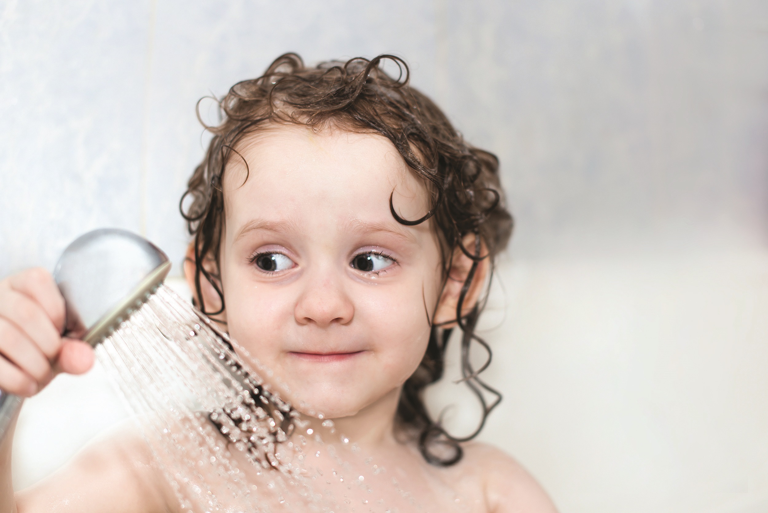 little girl in the bathroom holding a shower Heating & Plumbing